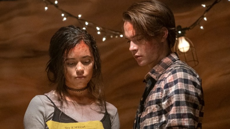 Jenna Ortega and Judah Lewis with blood on their faces in a horror film