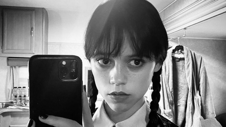 Jenna Ortega taking a selfie dressed as Wednesday Addams