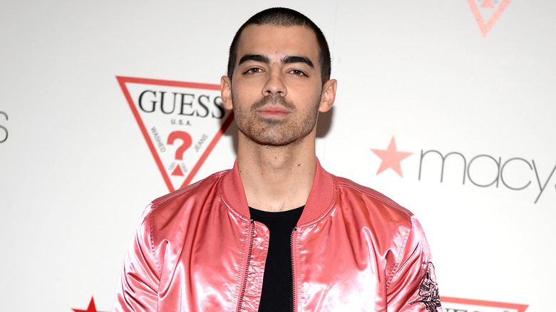 Joe Jonas posing at a Guess event
