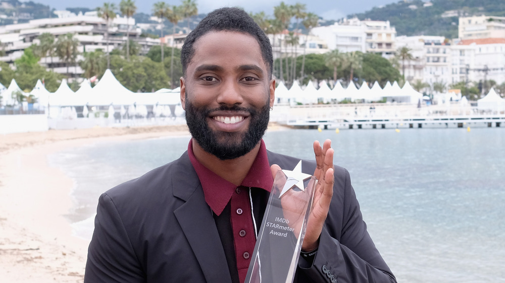 John David Washington on the beach in Cannes holding award