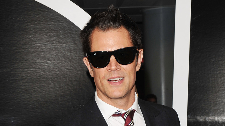 Johnny Knoxville in a suit and sunglasses