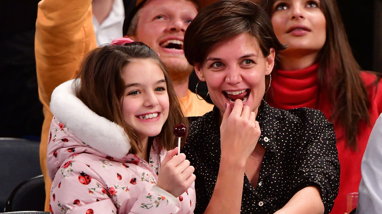 Suri Cruise and Katie Holmes, seated at sports event