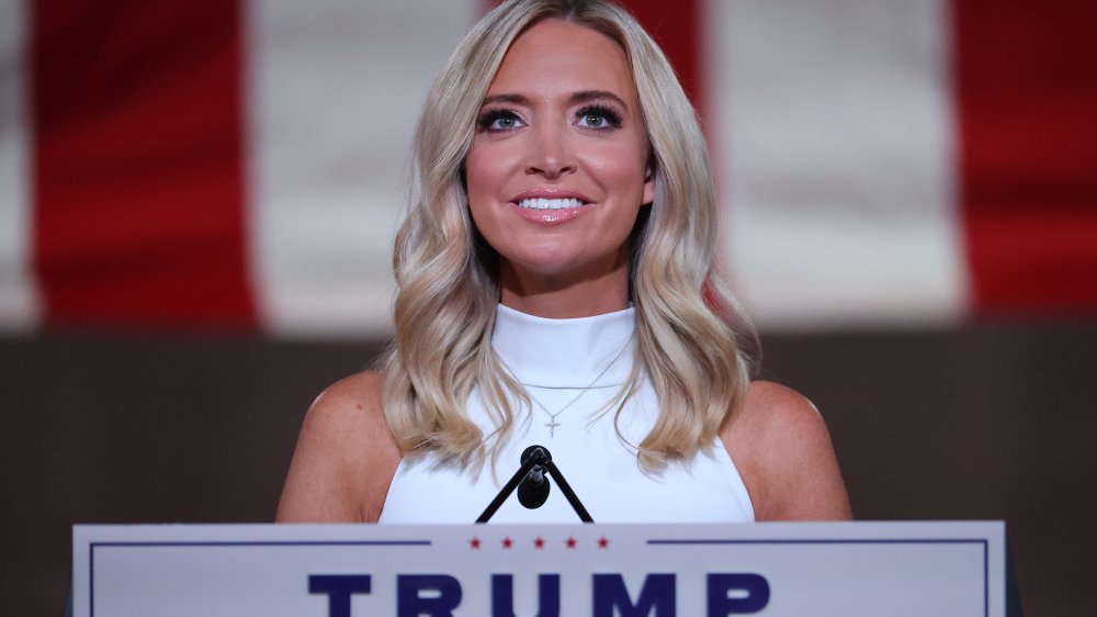 Kayleigh McEnany in a white dress, smiling while speaking at the 2020 RNC