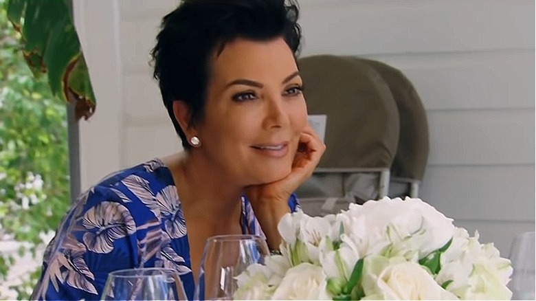 Kris Jenner in tropical shirt, next to white flowers