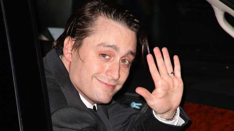 Kieran Culkin smiles and waves from inside car