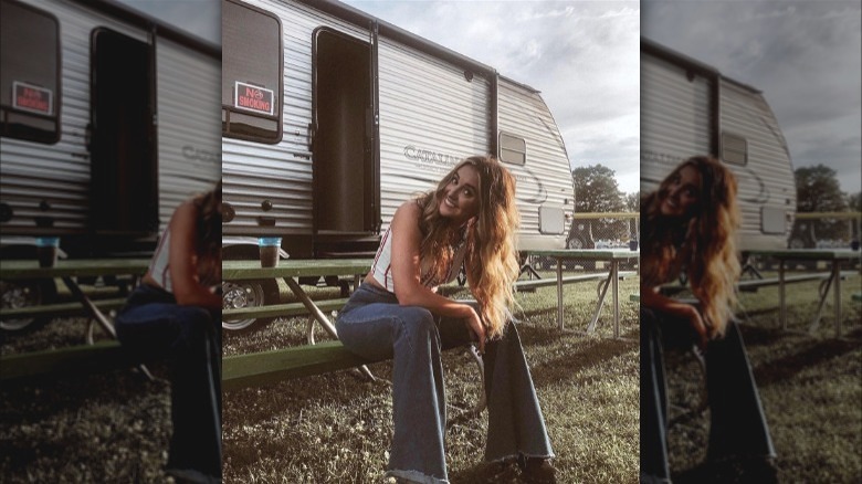 Lainey Wilson sitting near trailer