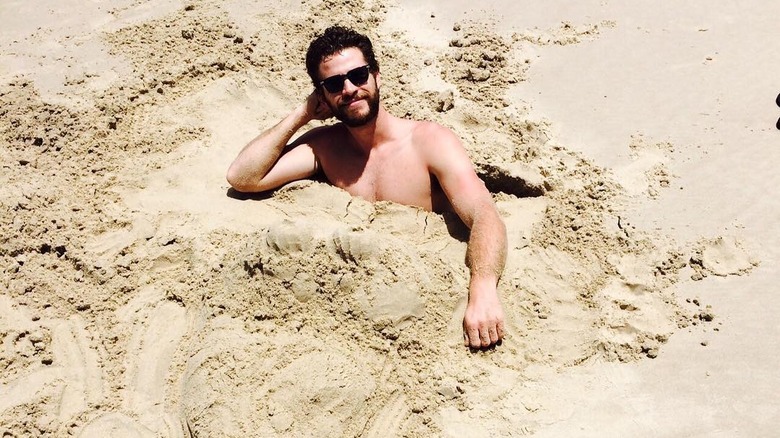 Liam Hemsworth buried in sand