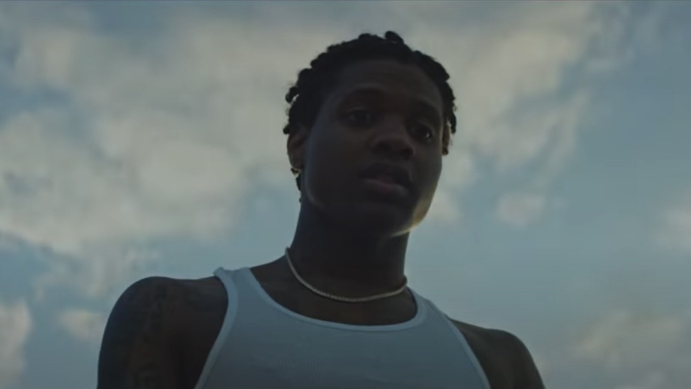 Lil Durk looking down, clouds above him