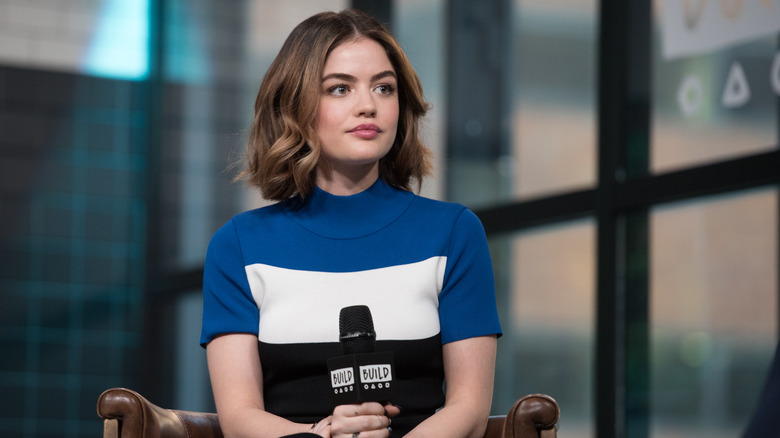 Lucy Hale sitting holding a microphone