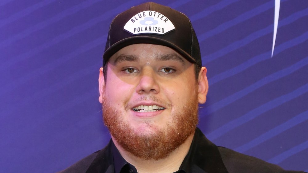 Luke Combs in a black suit and cap, smiling at the People's Choice Awards