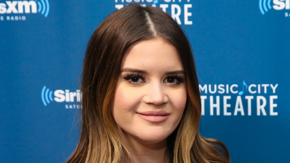 Maren Morris smiling in front of SiriusXM promo wall