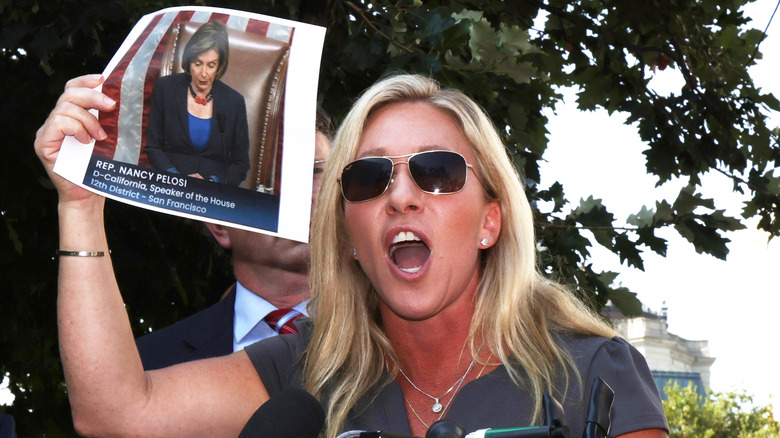 Marjorie Taylor Greene yelling and holding a photo of Nancy Pelosi