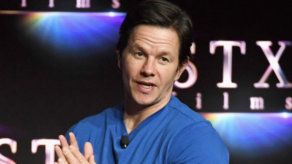 Mark Wahlberg in a blue shirt, speaking to a crowd