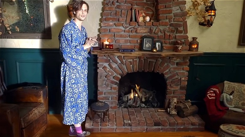 Matthew Gray Gubler standing in a kimono by his brick fireplace