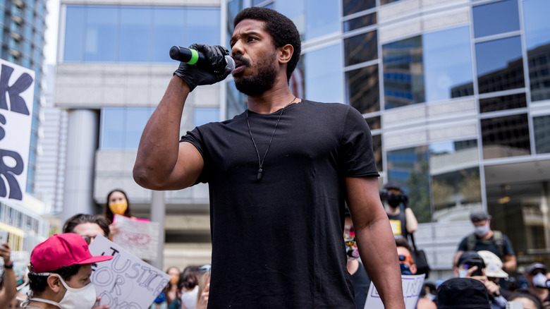Michael B. Jordan speaking into microphone at a protest