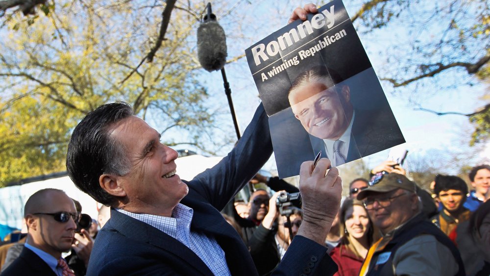 Mitt Romney holding a poster of his dad, George Romney