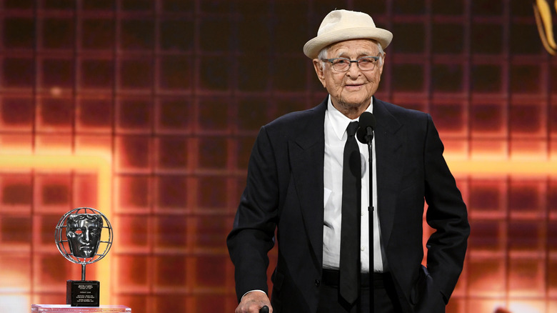 Norman Lear standing on stage next to an award