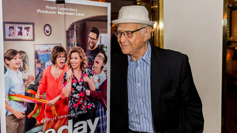 Norman Lear posing with poster for One Day at a Time