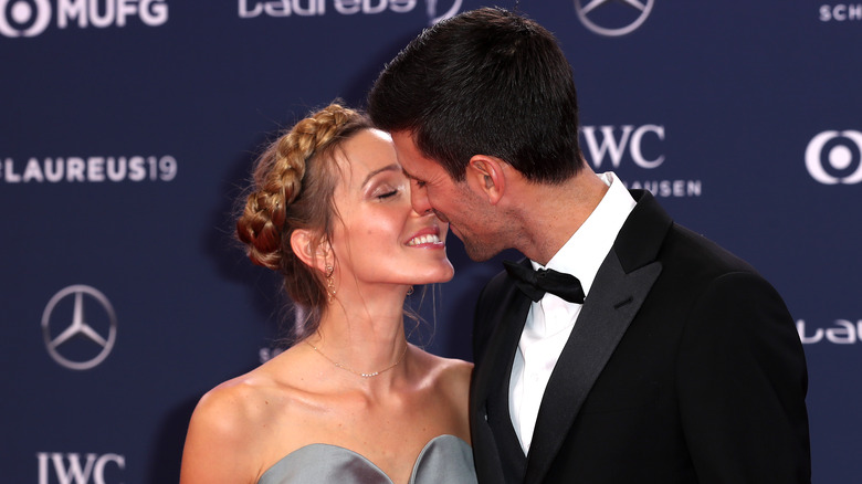 Jelena Djokovic leaning in to Novak Djokovic for a kiss 