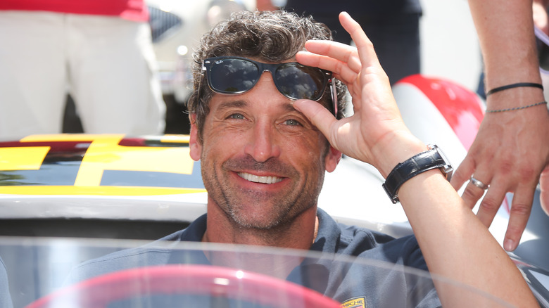 Patrick Dempsey in a car lifting his sunglasses off his face 