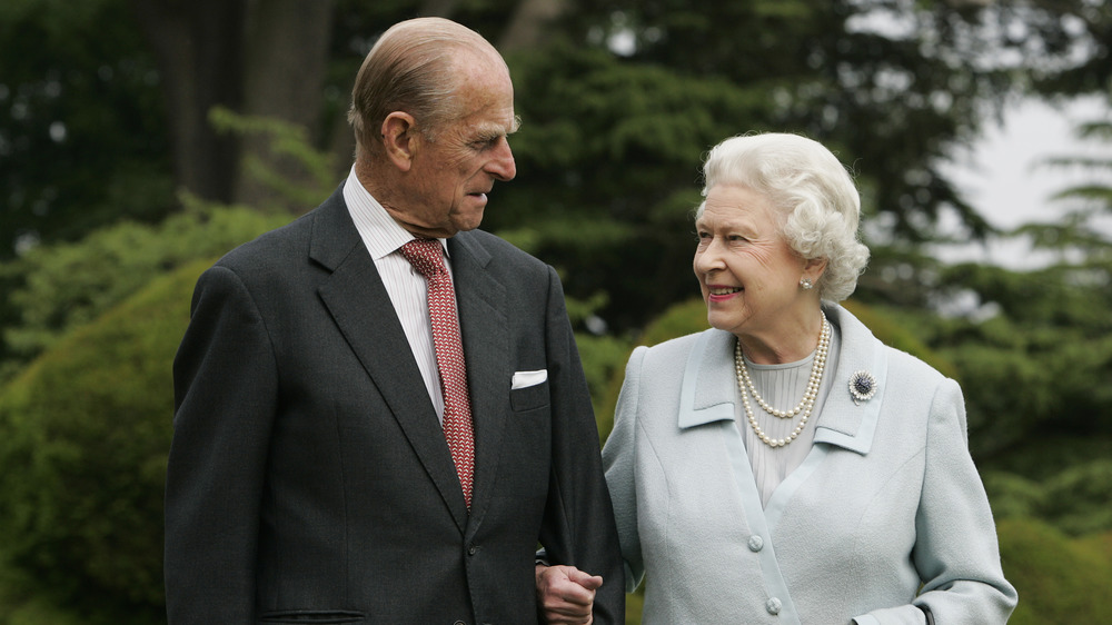 Prince Philip and Queen Elizabeth smiling at each other arm-in-arm