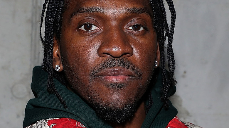 Pusha T wearing a red jacket, posing