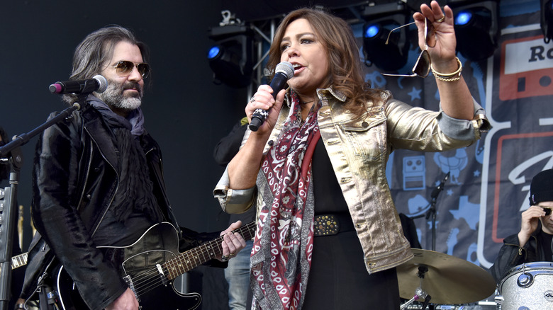 John Cusimano playing guitar and wife Rachael Ray speaking into microphone