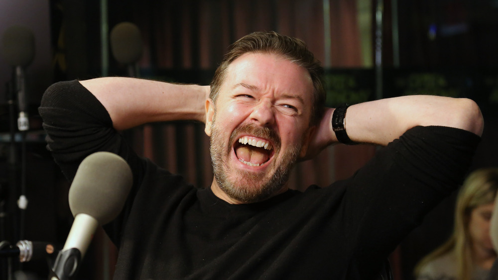 Ricky Gervais laughing at the microphone
