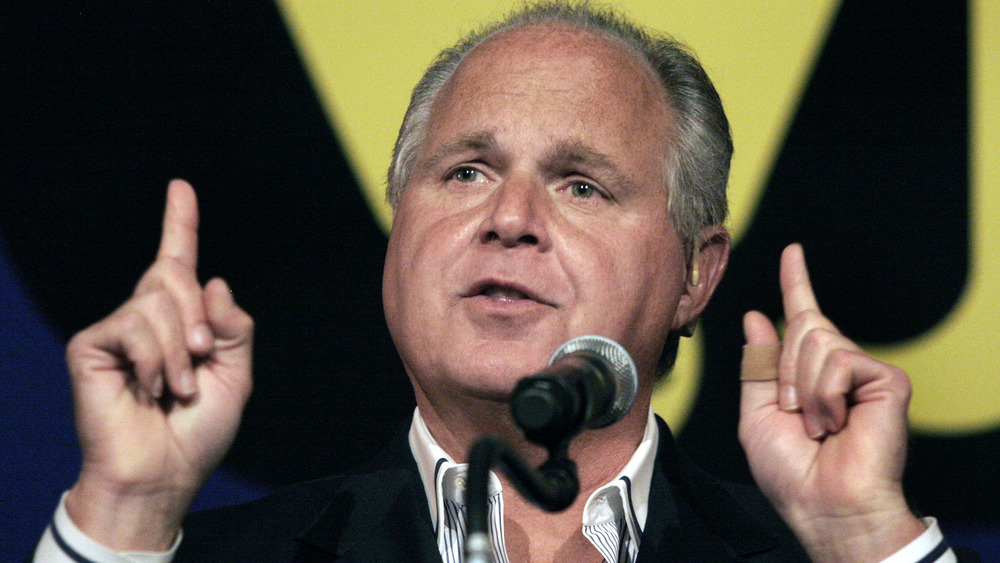 Rush Limbaugh speaking into microphone, fingers pointing up
