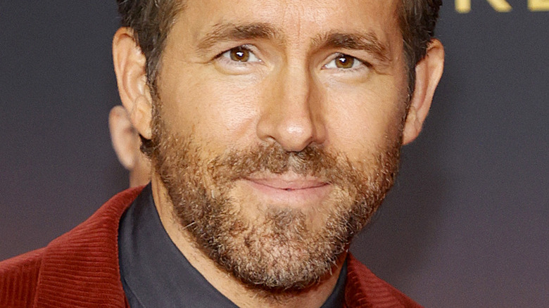 Ryan Reynolds wearing a red jacket, smiling