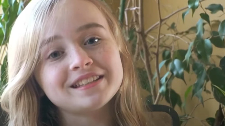 A younger Sabrina Carpenter, plants in background