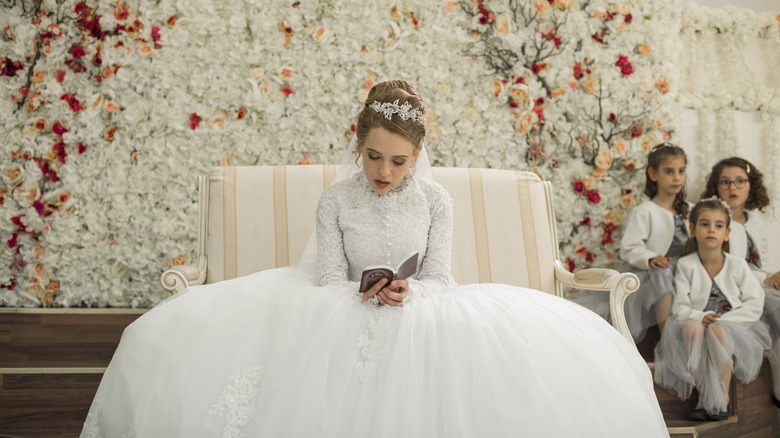 Shira Haas as Esty, reading while wearing beautiful dress