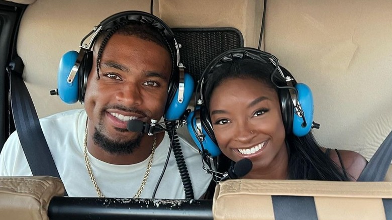 Jonathan Owens and Simone Biles wearing blue headphones and smiling