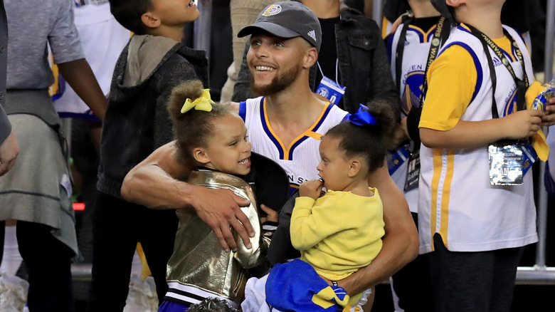 Steph Curry holding his daughters after a win