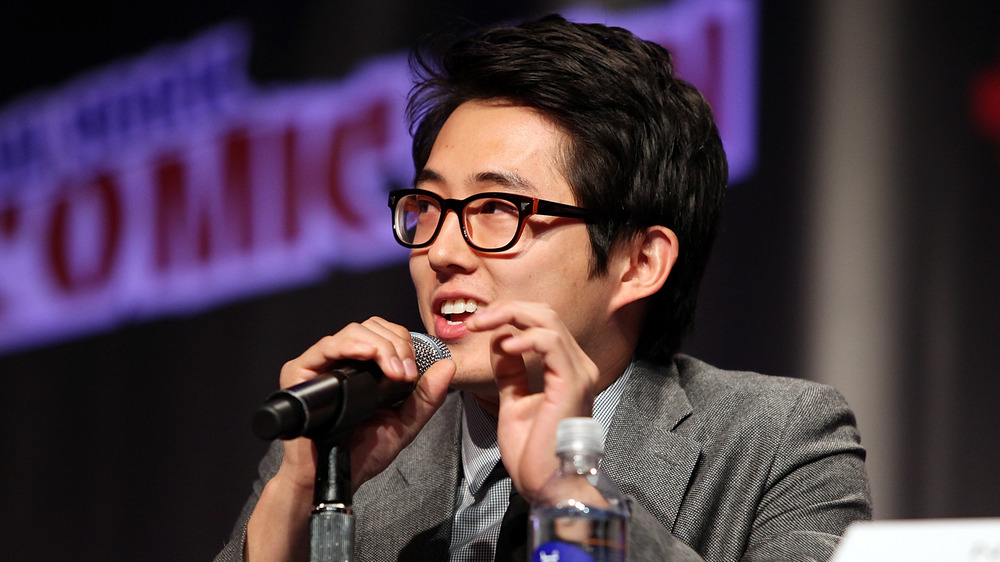 Steven Yeun speaking into a micrrophone at New York Comic Con