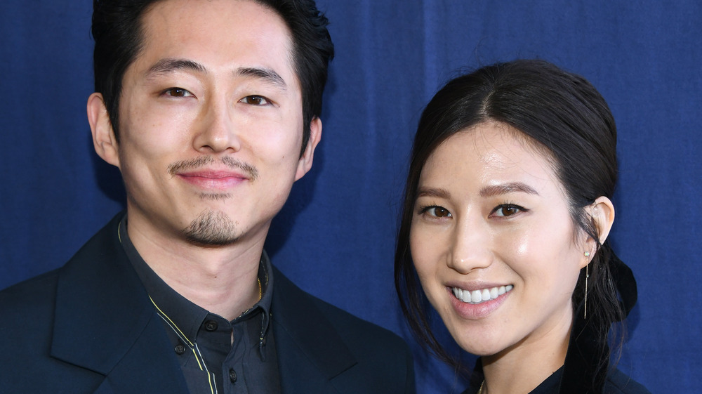 Steven Yeun smiling next to his wife Joana Pak