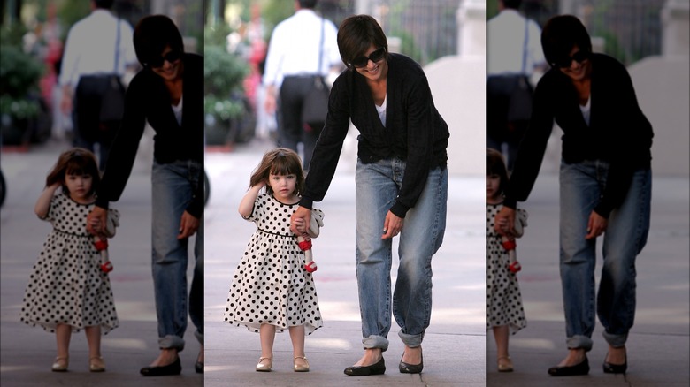 Katie Holmes leaning down beside Suri Cruise