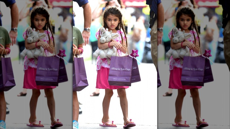 Suri Cruise holding bags, stuffed animal