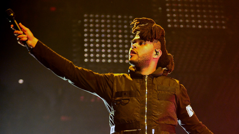 The Weeknd holding microphone high