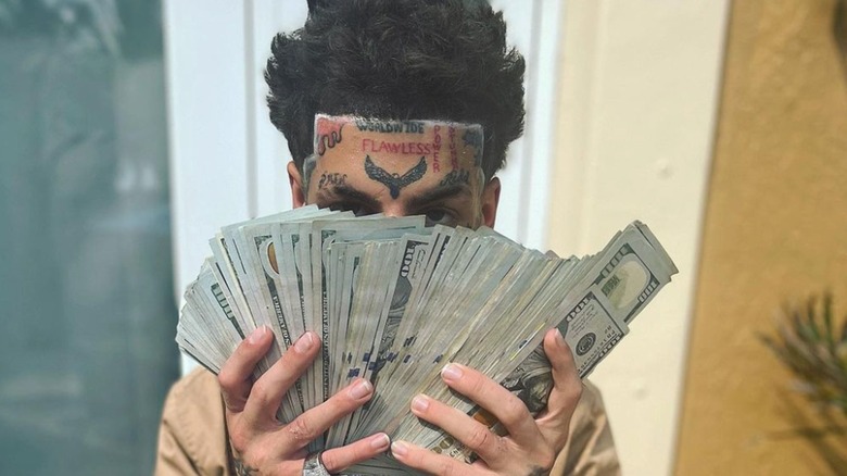 Kodiyakredd posing with cash in front of his face