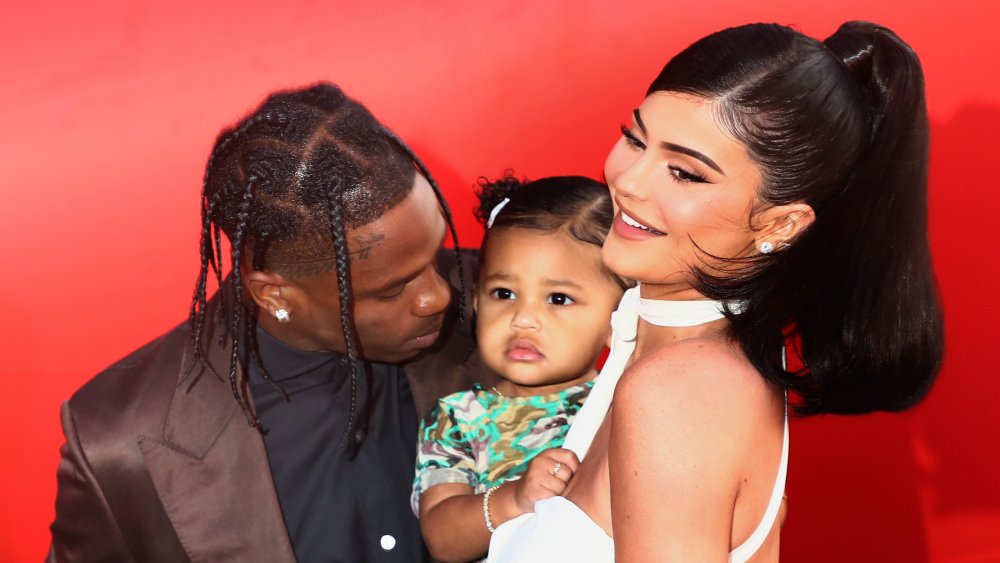 Travis Scott, Stormi Webster, and Kylie Jenner embracing on the red carpet 