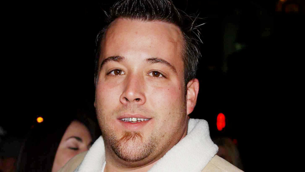 Uncle Kracker smirking, exposing a jewel on his tooth