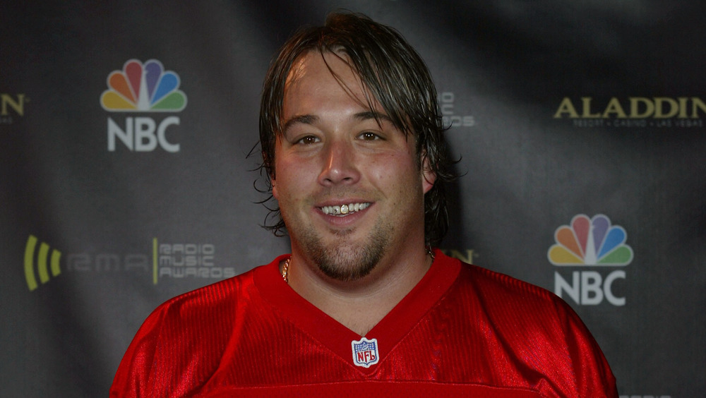 Uncle Kracker smiling, sporting greasy long hair 