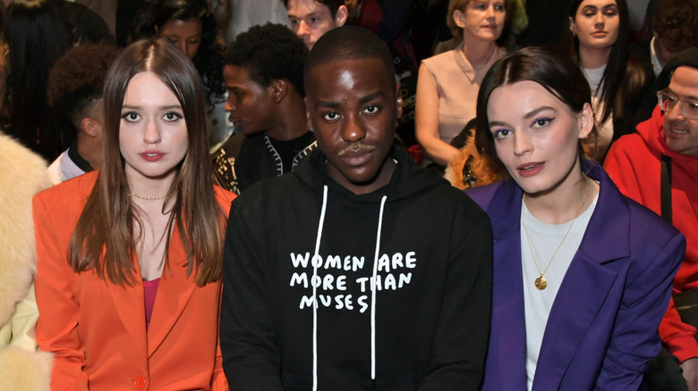 Aimee Lou Wood, Ncuti Gatwa, and Emma Mackey sitting at a fashion show and smiling