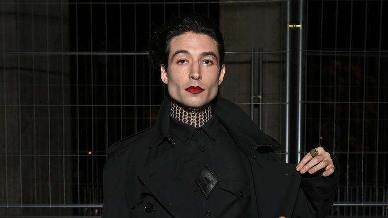 Ezra Miller dark jacket hand raised posing