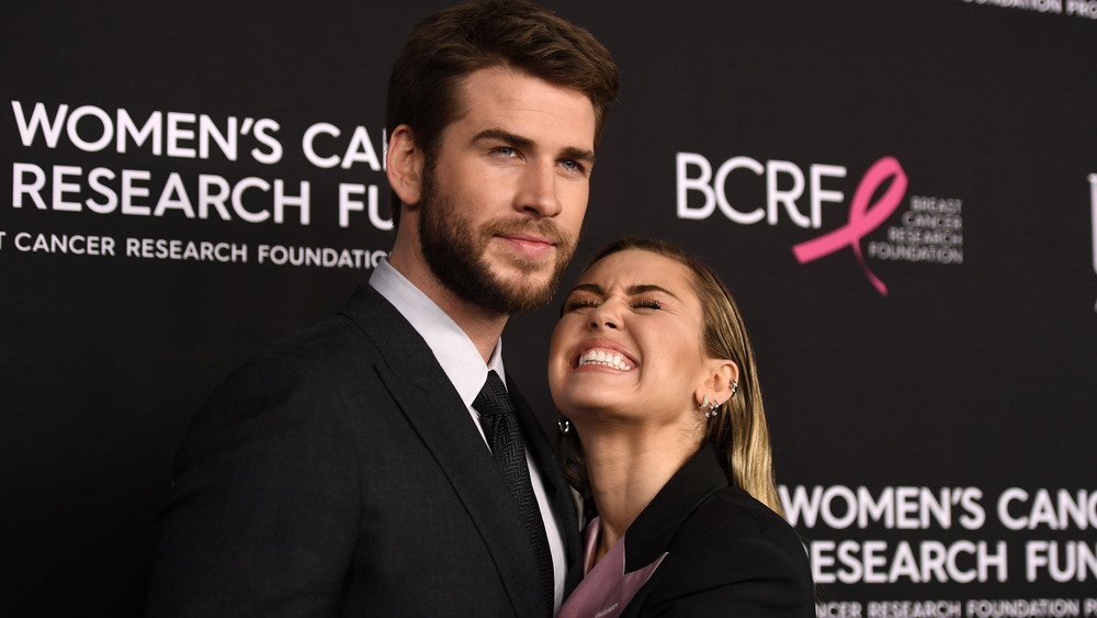 Liam Hemsworth hugging a cheesing Miley Cyrus