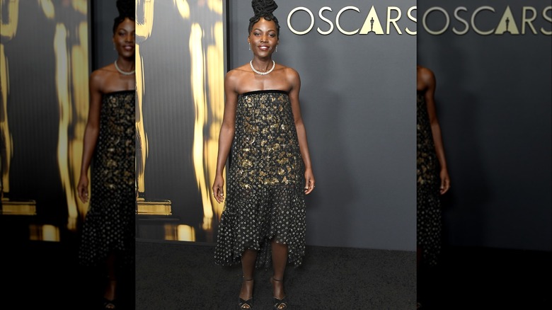 Lupita Nyong'o with an updo and black and gold Chanel dress