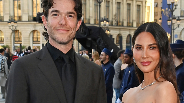 John Mulaney and Olivia Munn posing outside at an event