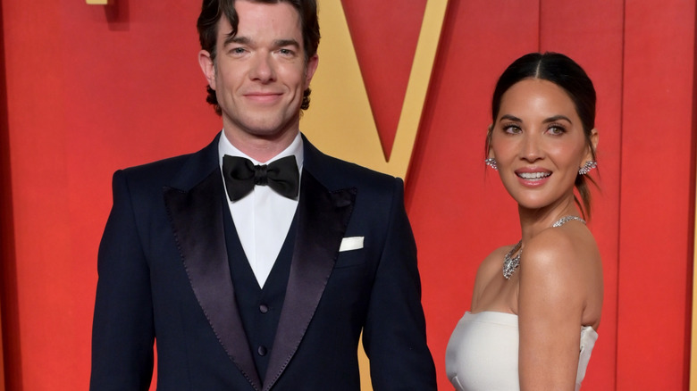 John Mulaney and Olivia Munn attending an award show and posing in formalwear