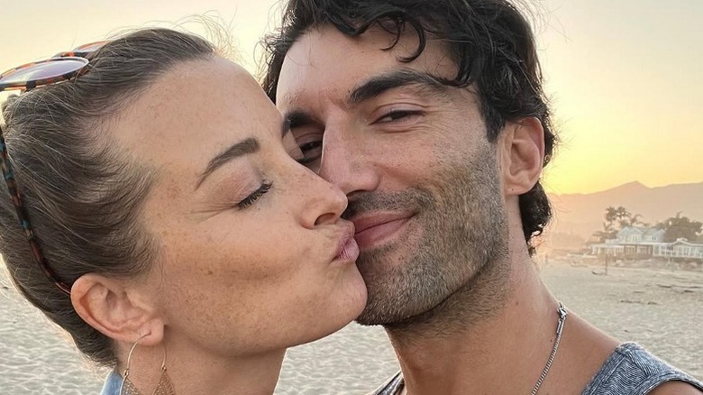 Emily Baldoni and Justin Baldoni smooching each other on the beach